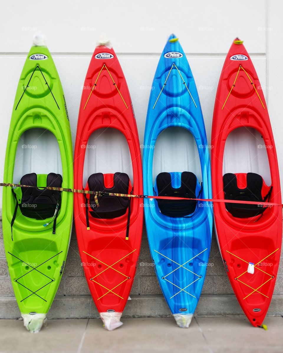Red blue and green kayaks against a wall It's Summertime
