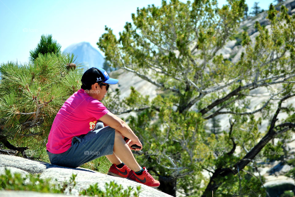 Man, boy, sitting on top a mountain, relaxing, looking at the view