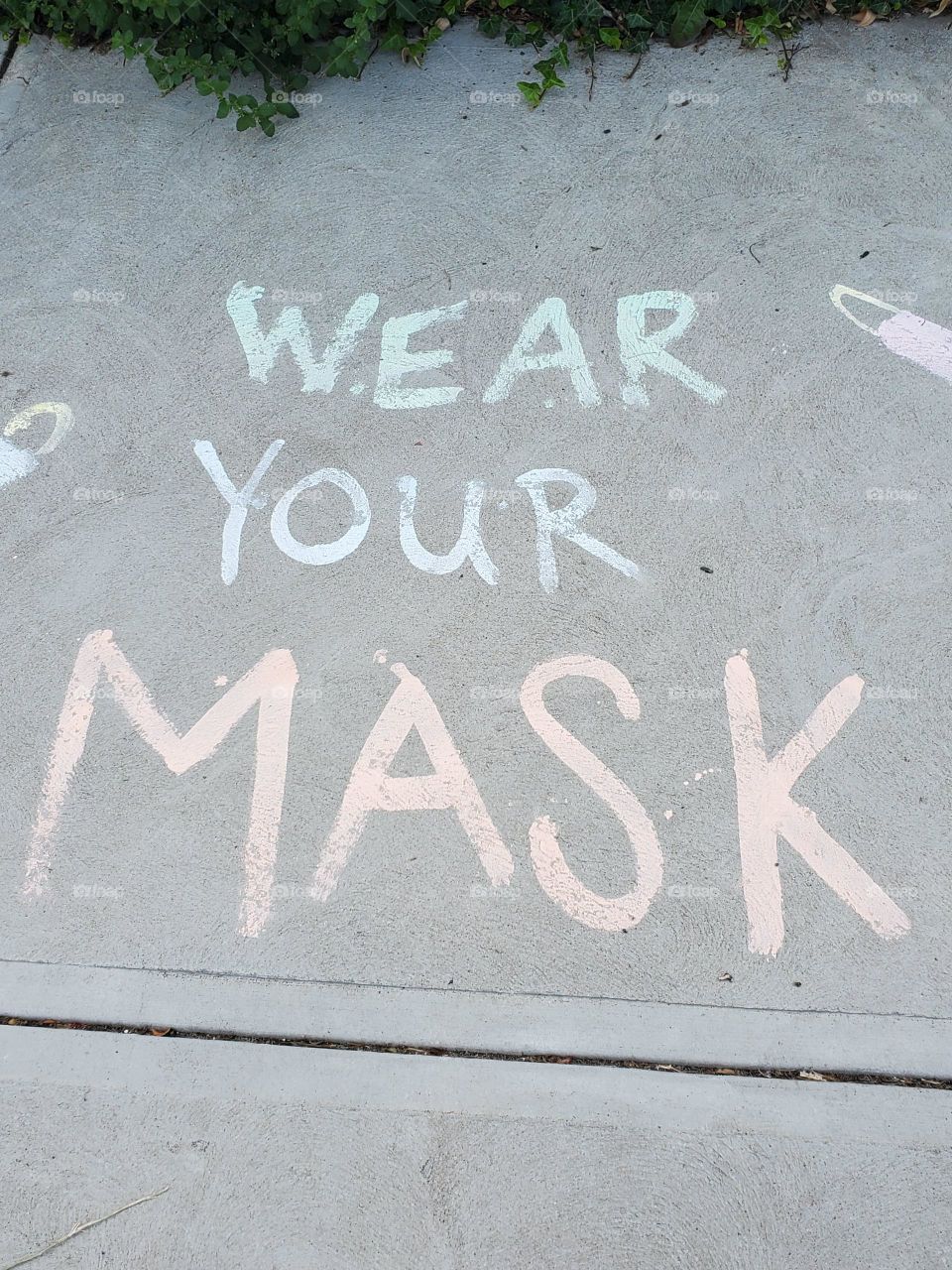 a message to wear a mask written on the sidewalk