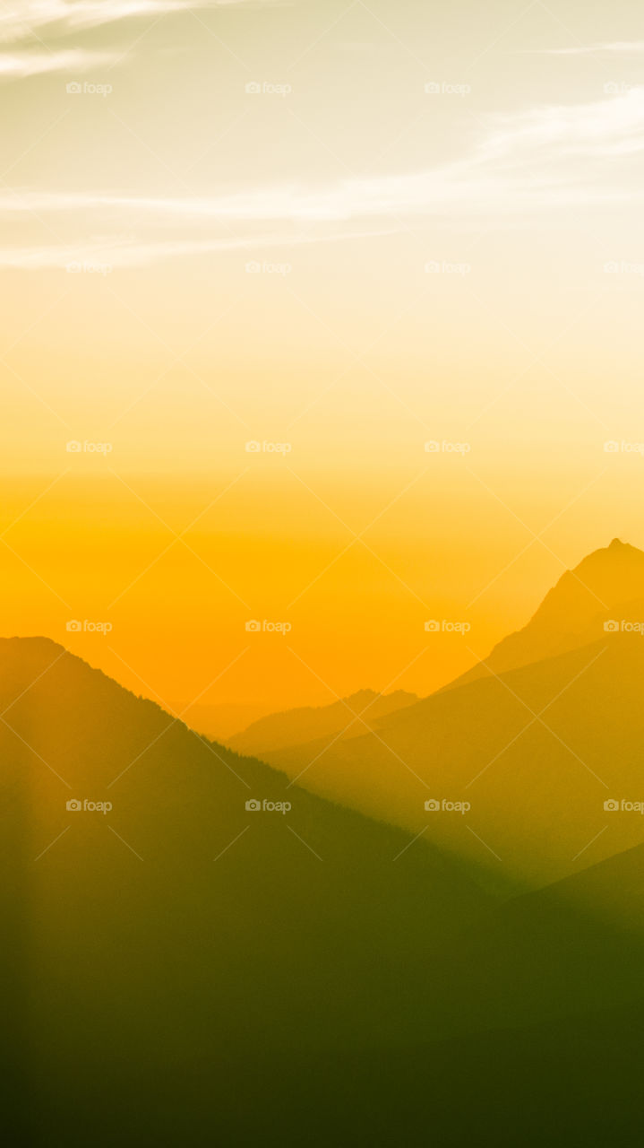 An inspiring mountain landscape. Tatry mountains in Slovakia. A beautiful wallpaper for smartphone screen. Warm summer haze, abstract gradient with perspective.