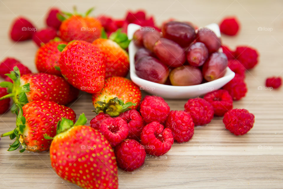 Close up of red fresh summer berries including strawberry grapes and raspberries. Fresh fruit for a healthy lifestyle