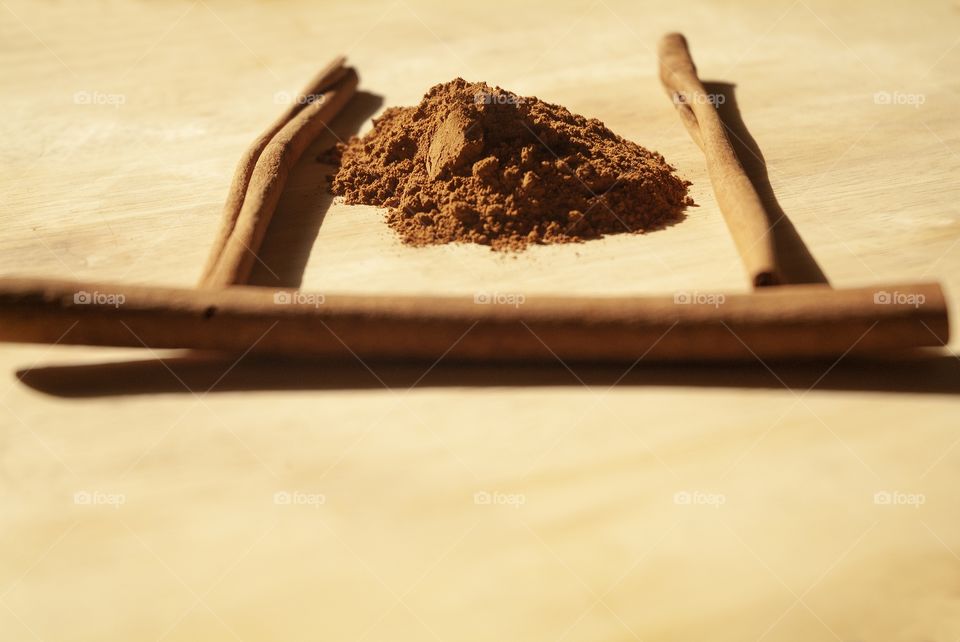 Cinnamon sticks and powder rest side by side on a wooden cutting board.