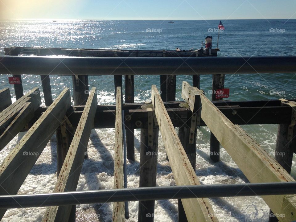 A view of the ocean from the pier in Ocean Grove, NJ. In the distance on the right is a figure which is a stuffed “fisherman” named Ralph. For a long time, he sat on the end of the pier until he got washed away in a storm that damaged the pier.
