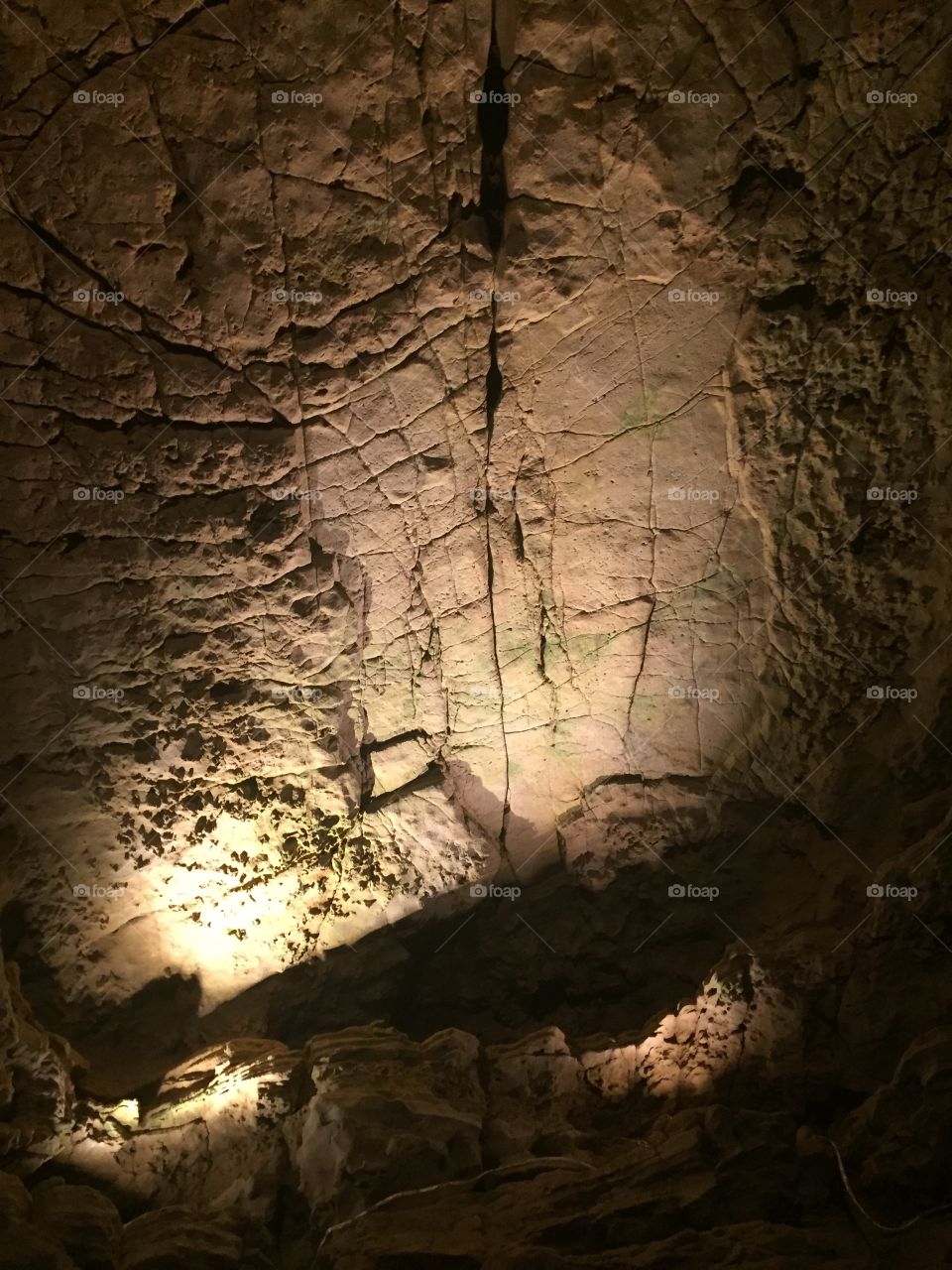 A spotlight shown on the wall of a cave producing a stunning display of light and shadow