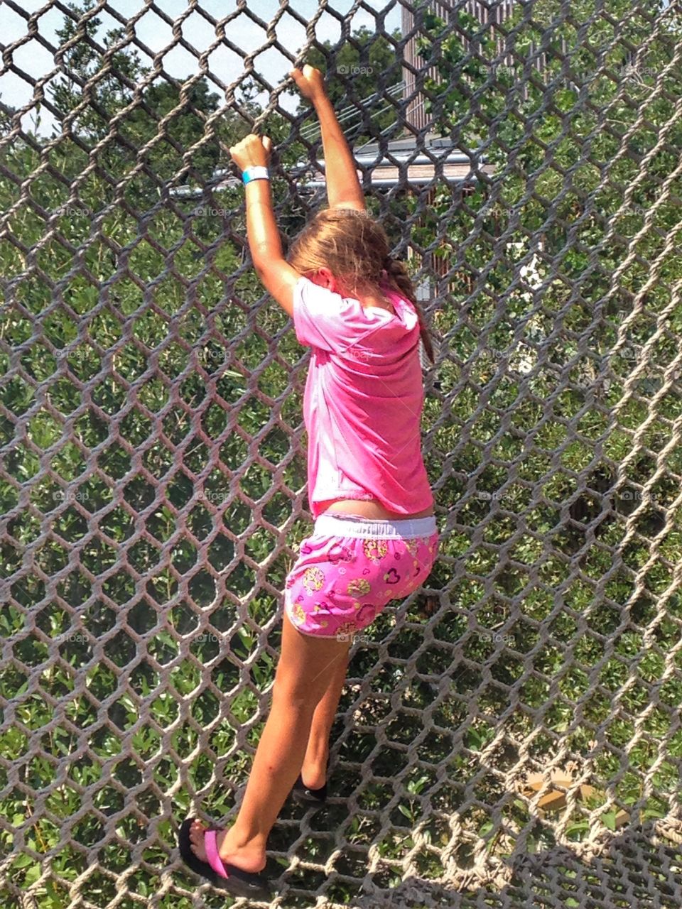 Strength training. Girl climbing a rope wall