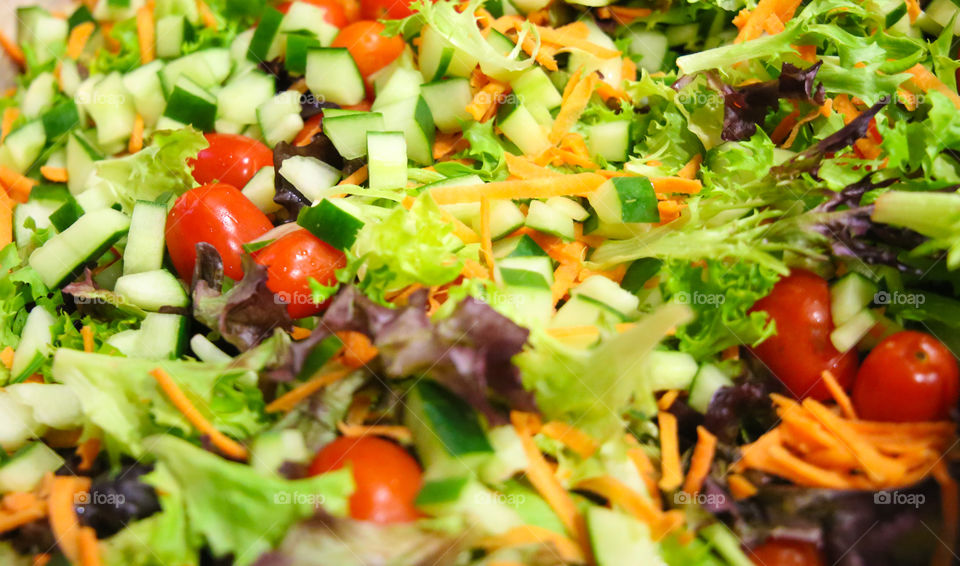 Super healthy organic mix of greens, tomato and cucumbers chopped and made into a colorful salad