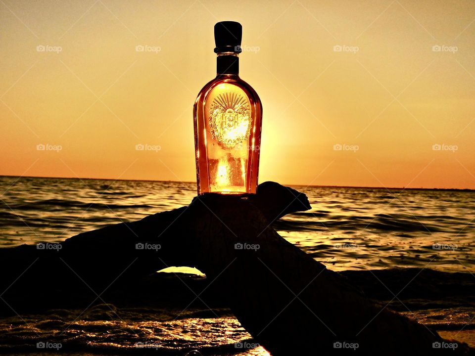 Blue vs Yellow - a magnificent descending golden sunset passes through a decorated bottle sitting on a tree limb 