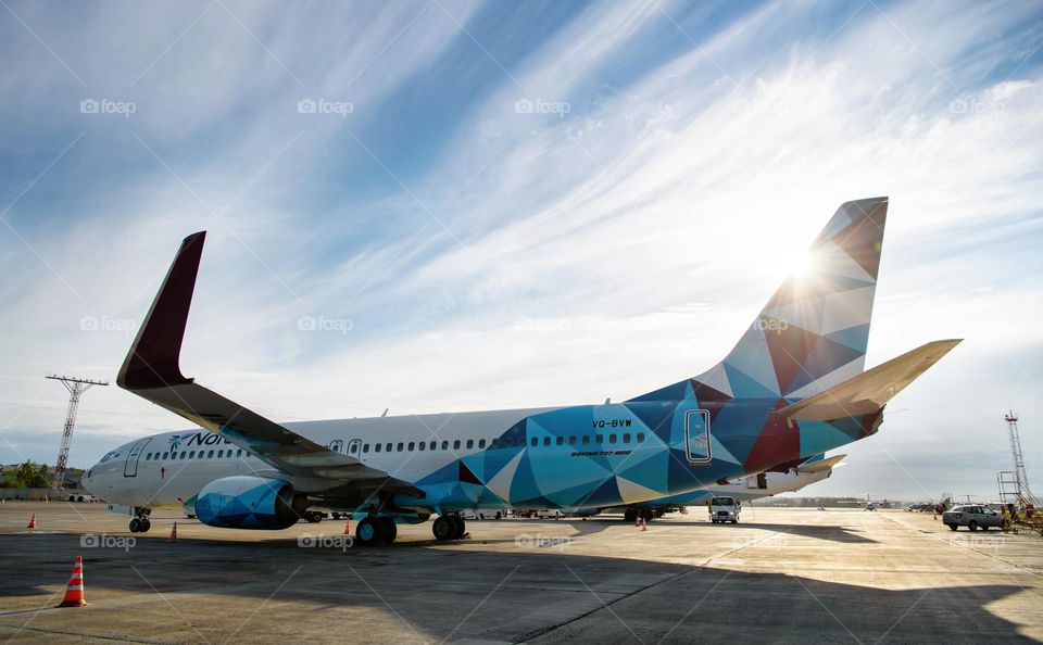 Aircraft in blue livery in the parking lot.  unusual clouds