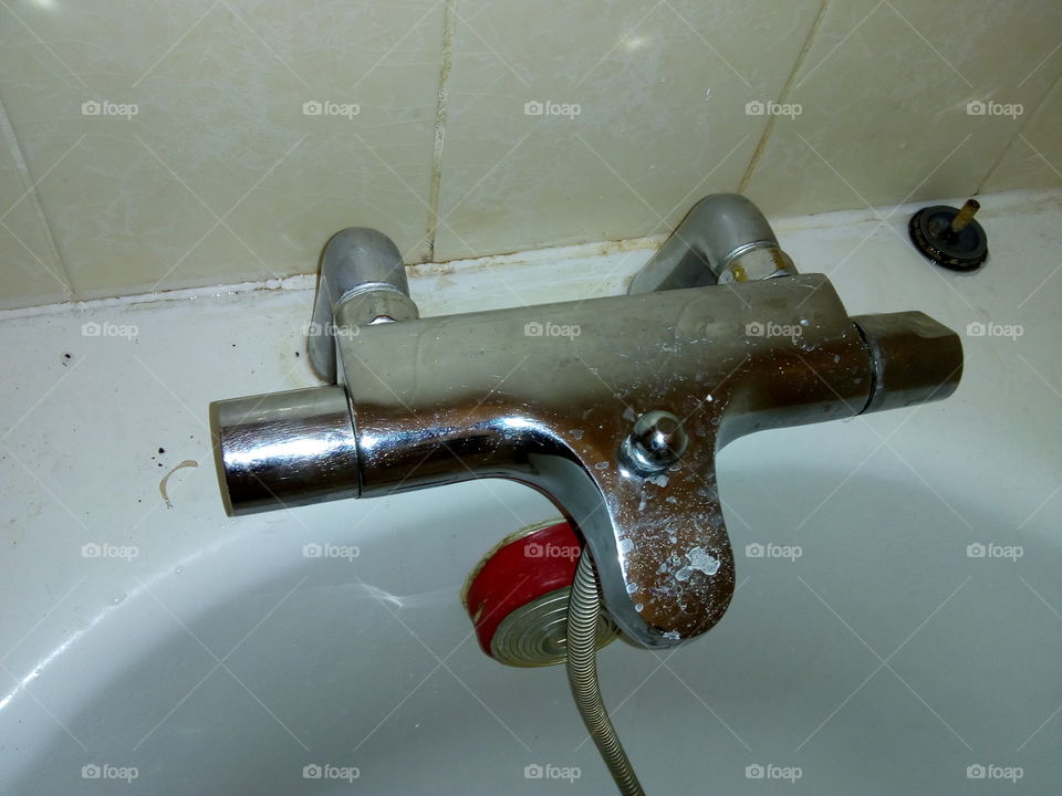 dirty bathtub tap waiting to be cleaned up in bathroom