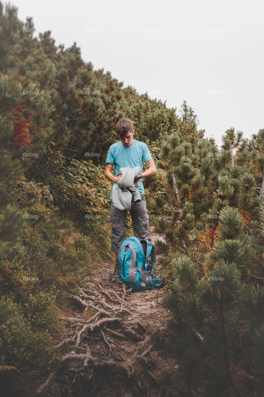 Teenage boy with backpack in forest