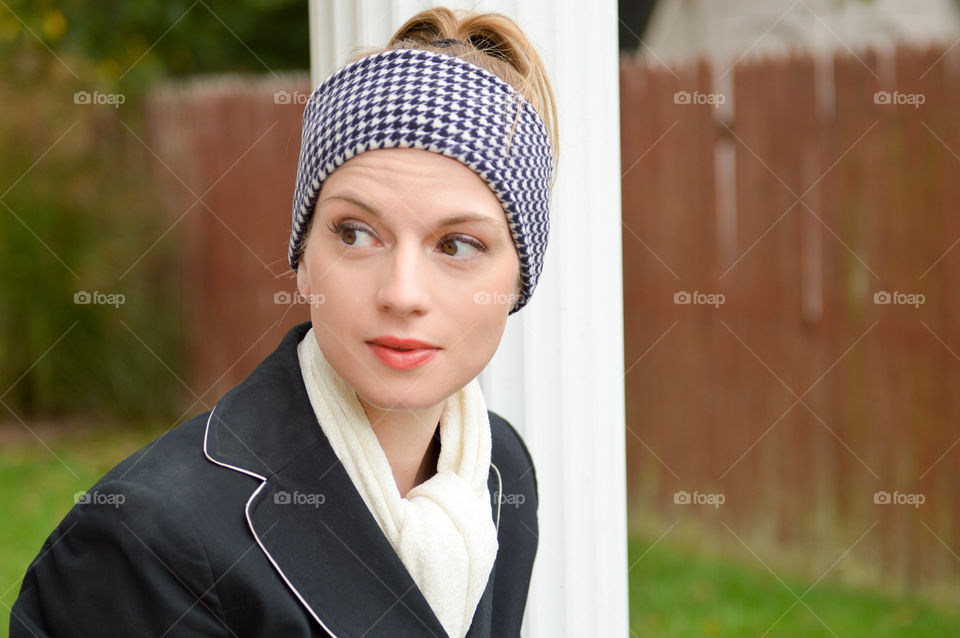 Woman wearing a houndstooth print headband and white scarf outdoors