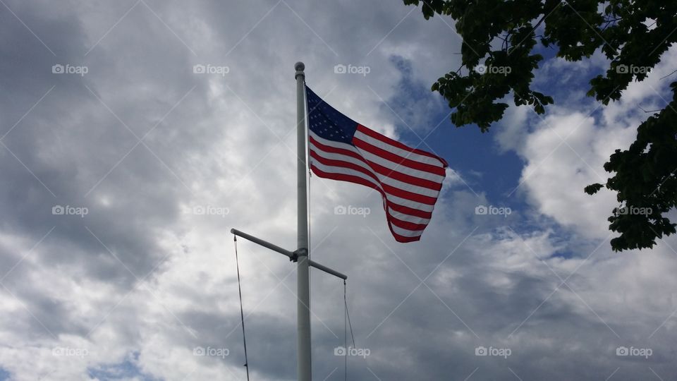 The Mast of a yacht displays a USA flag on the wind after the rain. Outside Boston, USA.