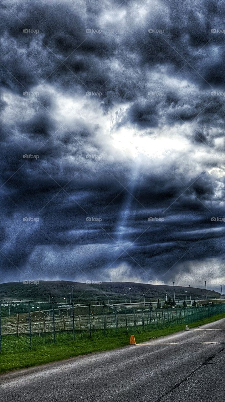 moody dark skies, fluffy clouds, ray of light, landscape