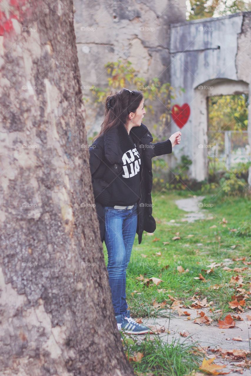 Woman showing painted heart on wall at park