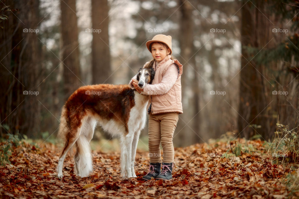 Cute smiling girl with borzoi dog in an autumn park 