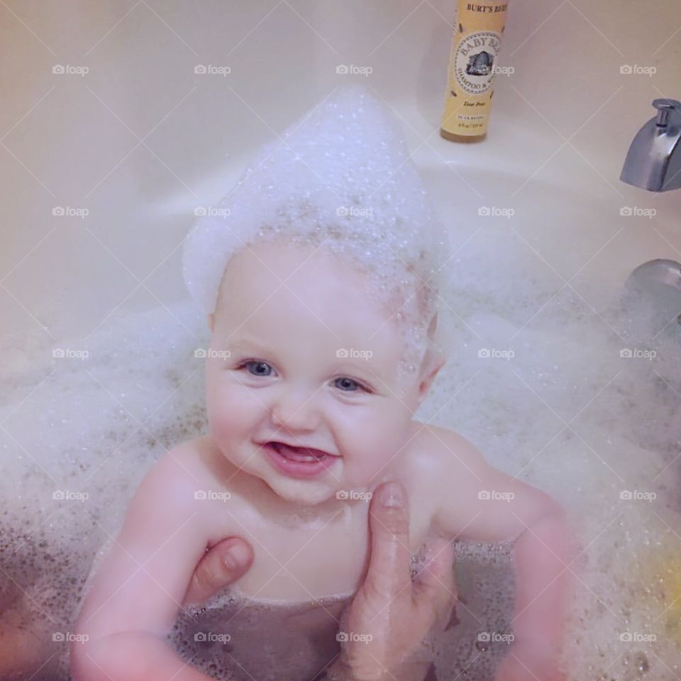Happy baby taking bath in bathtub