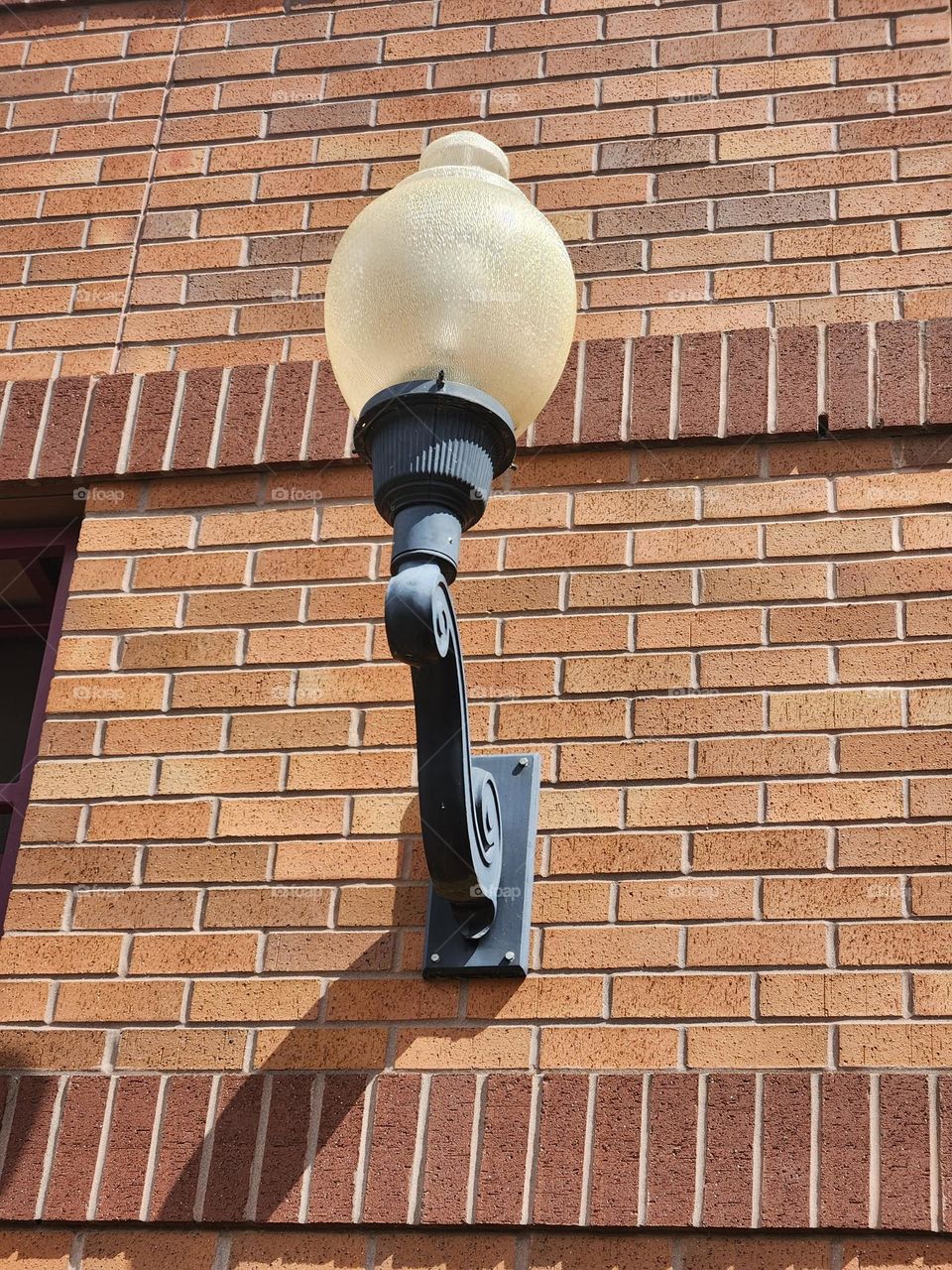 ornate outdoor light fixture on brown brick wall