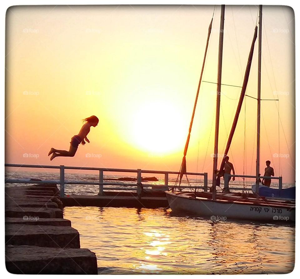 A boy jumping from the dock sunset