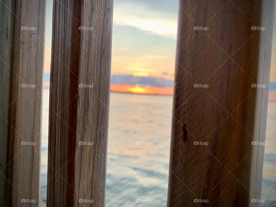 Sunset In The Horizon With Deep Orange Color Sighting From Gazebo On The Dock By The Island Reflecting On The Water.