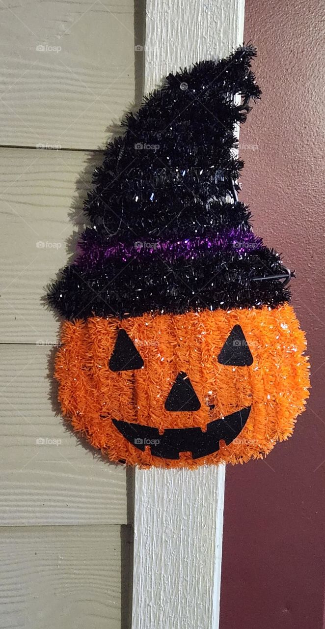 orange Jack O' Lantern wearing a witch hat grinning spooky cute outdoor Halloween decoration on a home in Oregon