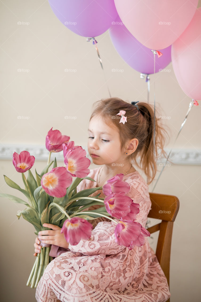 Birthday portrait of a beautiful little girl with tulips bouquet 