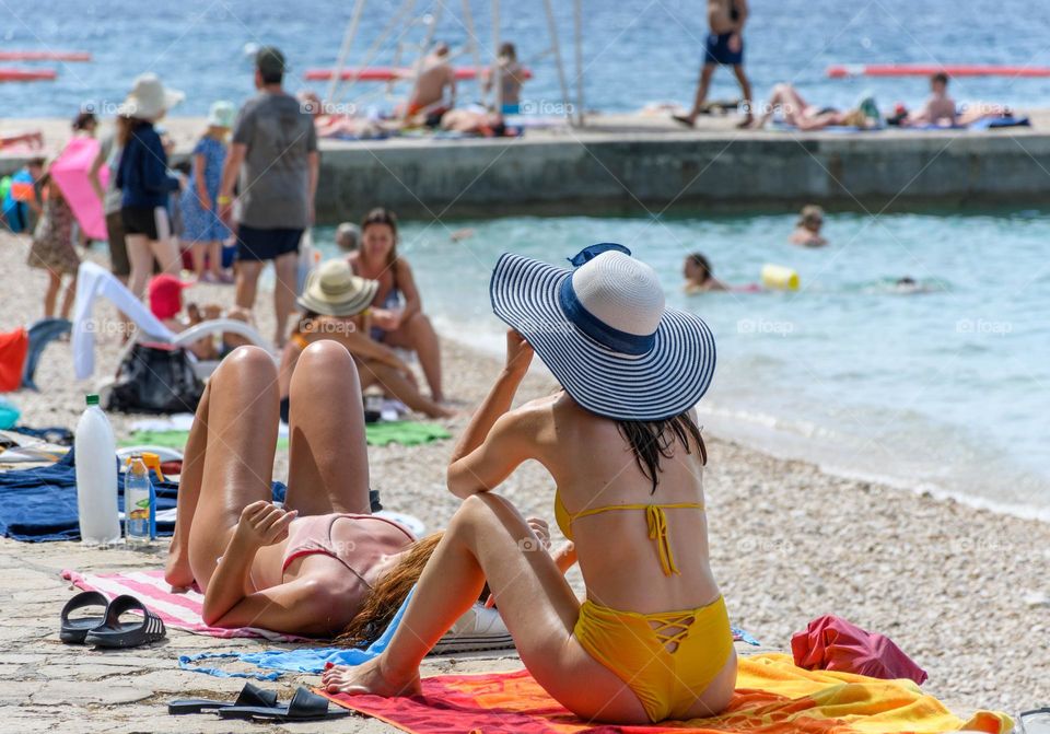 People sunbathing on a beach on a sunny hot day during summer