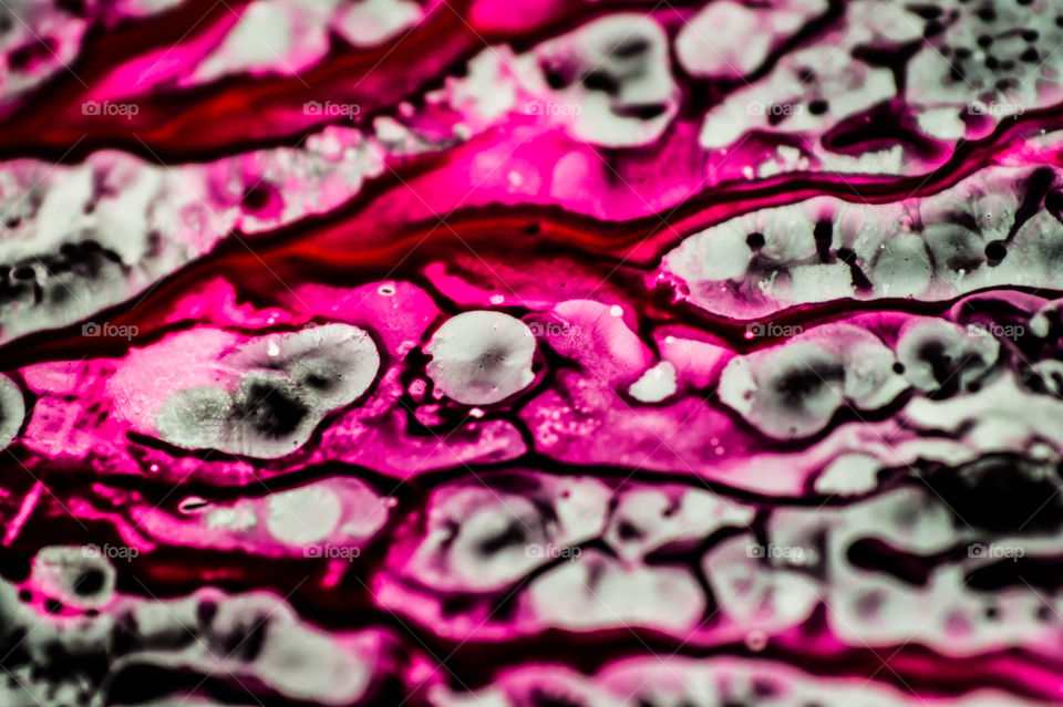 Black and pink refill ink spilled onto the white sink and the ink mixed into abstract blobs and patterns.