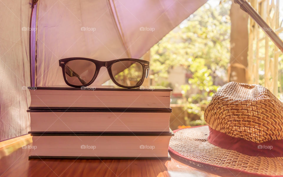 Defending light beams with umbrella. Umbrella protecting beautiful woman things. Books sunglasses and a straw hat. Summer holiday concept with copy space room for text.