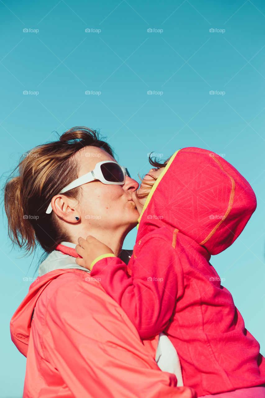 Love of mother and daughter. Mother hugging with her little daughter outdoors. Having fun, enjoying summer vacations