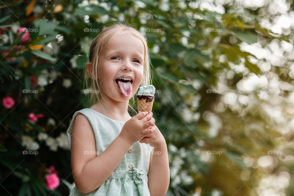  Cute little girl with blonde hair eating ice cream outdoor 
