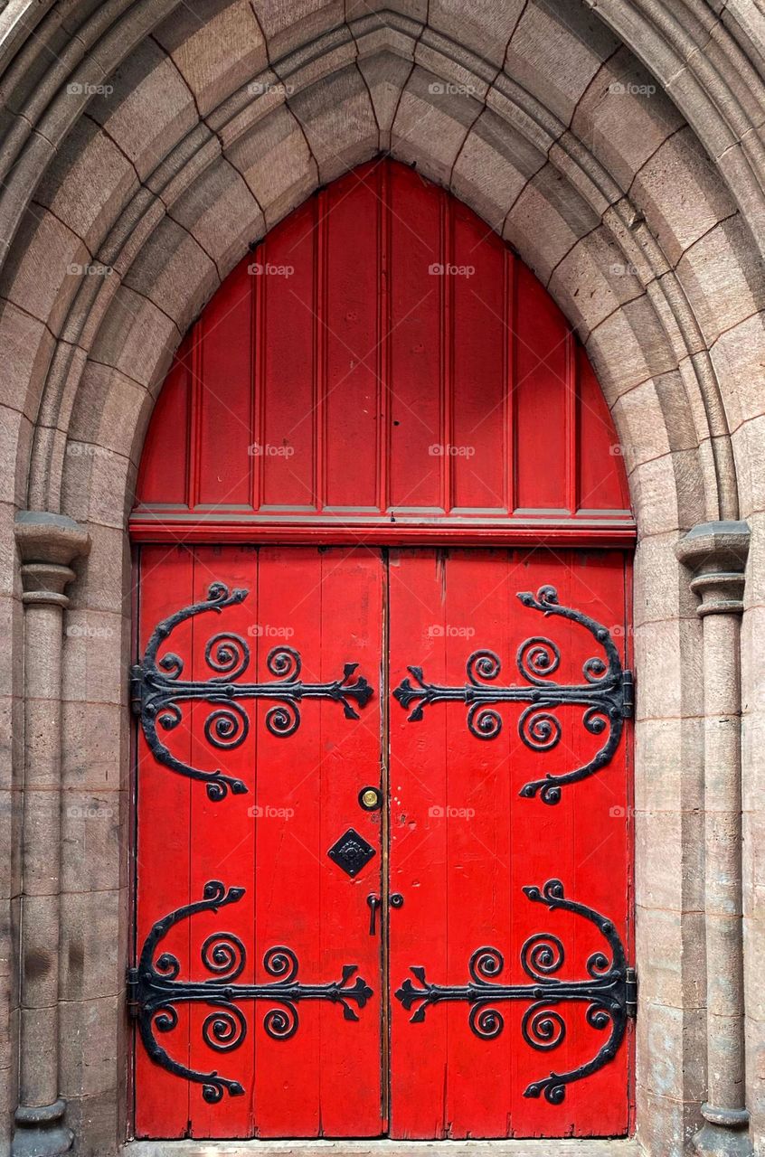 Red church door with elaborate iron hinges