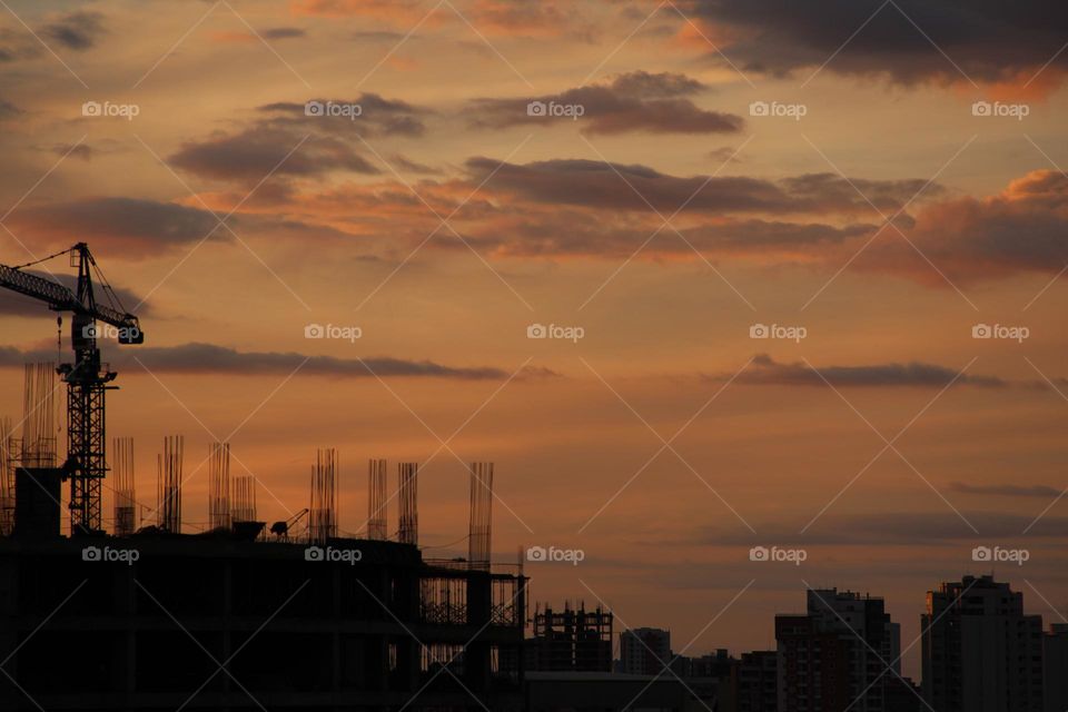 Atardecer de un skyline citadino con una construcción contrastada en primer plano 