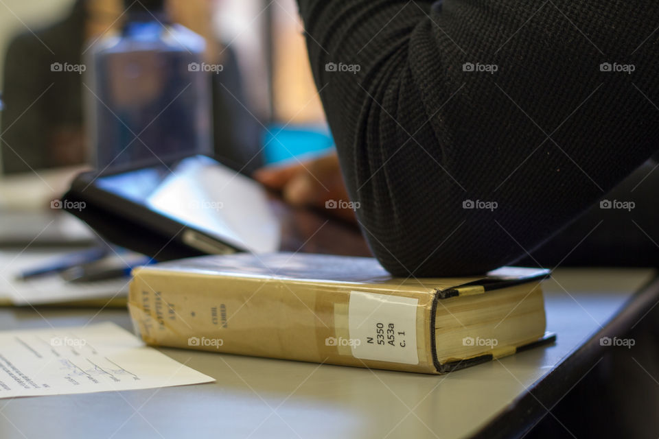 A man places his elbow on a library book while studying