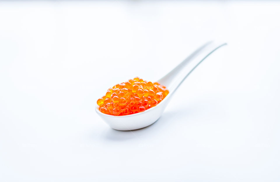 Salmon caviar in a white spoon. Minimalistic concept.