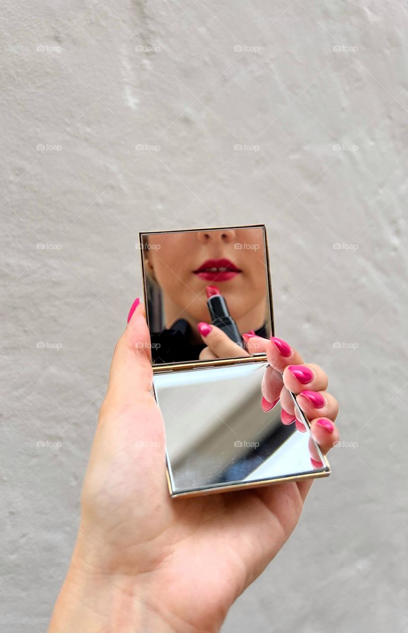 Reflection on the mirrors. Young woman. Lips, lipstick, manicure.