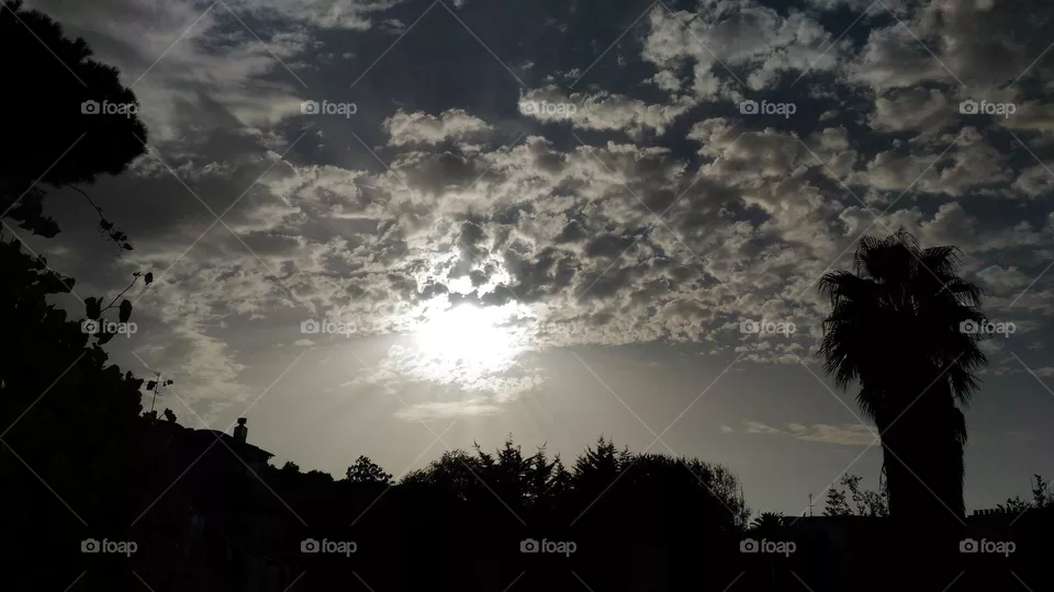The silver ball of the sun wrapped by soft clouds