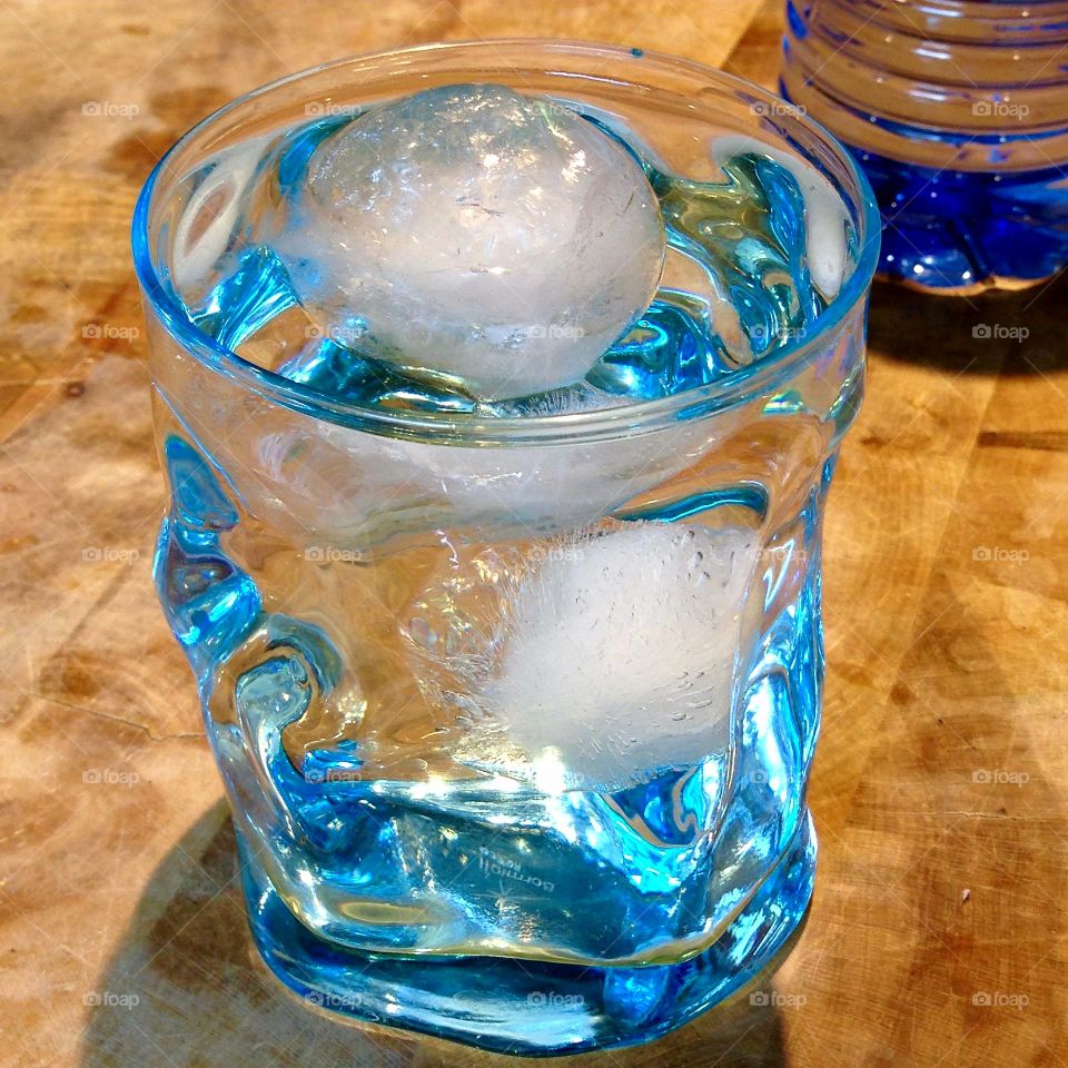 Glass of water, round ice cubes, chopping block, pure.
