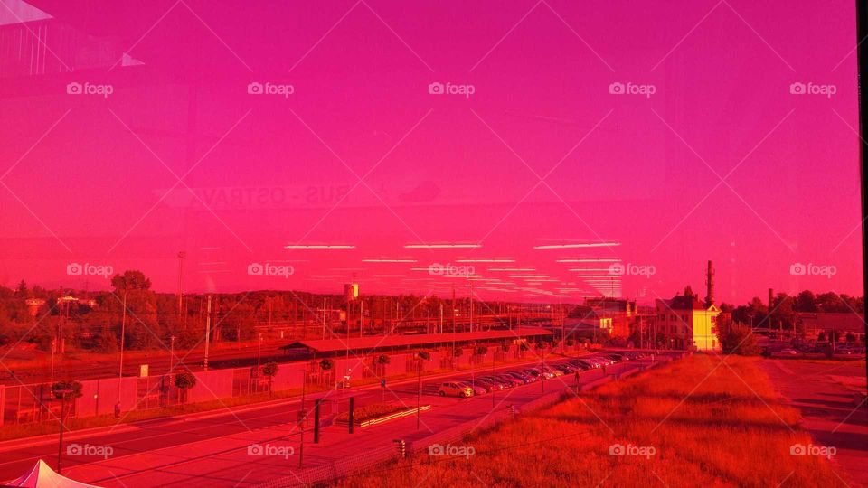 View through a glass covered by a red-pink foil. Bus station, Ostrava, Czechia.