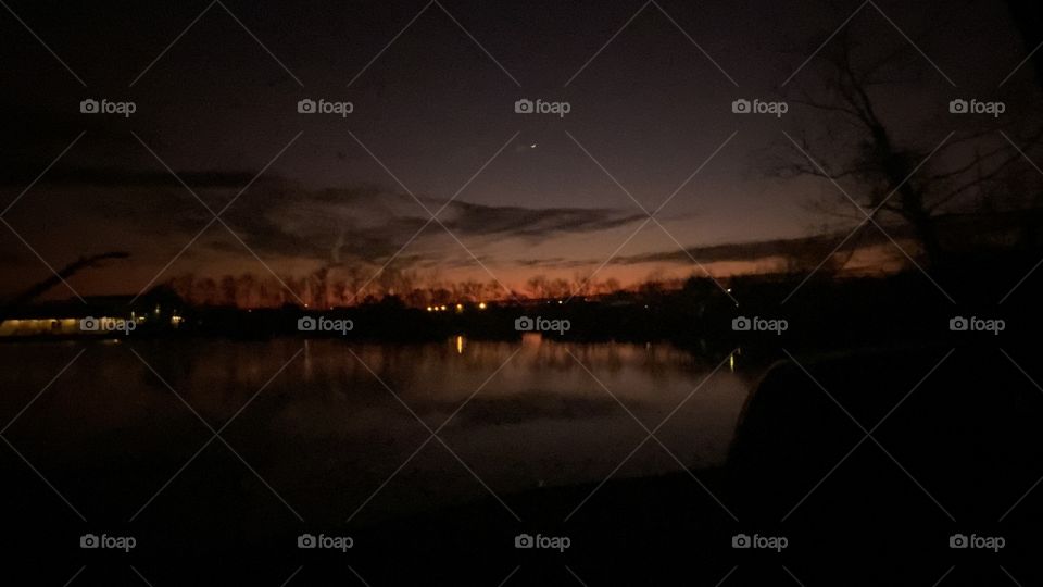 Long Exposure Photo with Picture Prefect Clear Night Reflections of Land Shore Can still be Seen. Trees. Lake Waters Calm. Horizon Colors from Backlit Night. Beautiful.