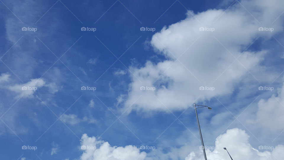 Fluffy white clouds hang in a crystal blue sky.