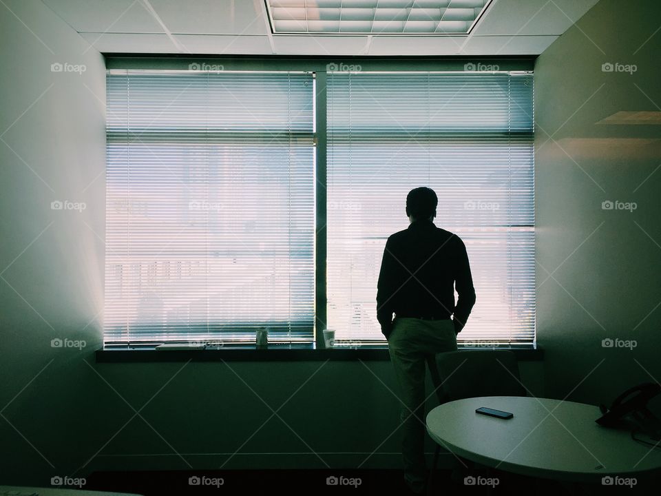 Man standing in his office cabin and thinking 