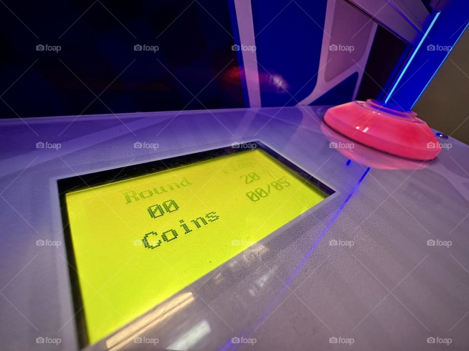 Game machine closed-up with green screen with coins counter and a push button ready to play.