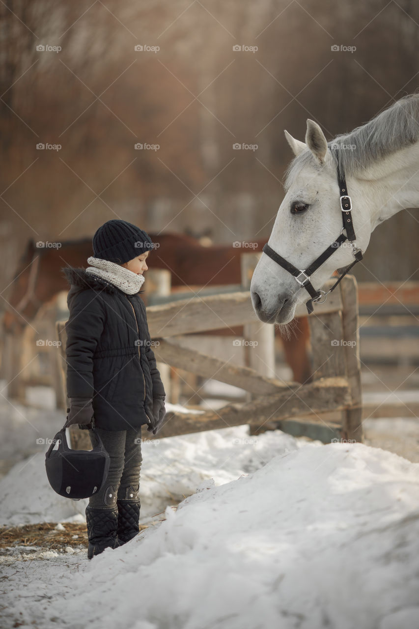 Little girl with horse on paddock 