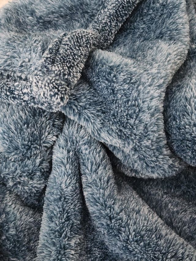 close up of a cozy blue gray plush comfort blanket to curl up in at home