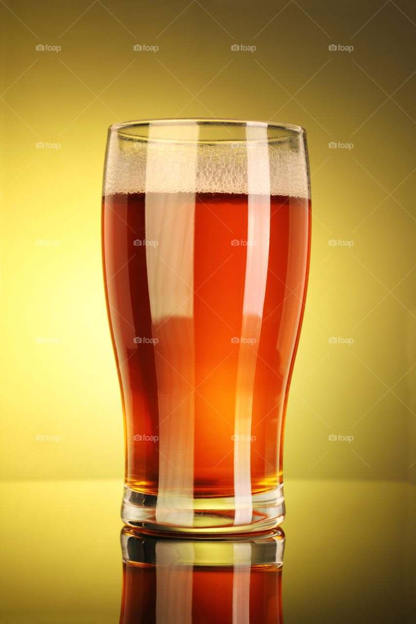 Full beer glass in yellow background