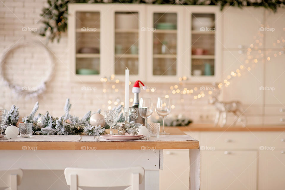 Festive winter cozy kitchen interior with garlands, decorations and gifts.  Christmas dinner at the decorated table.