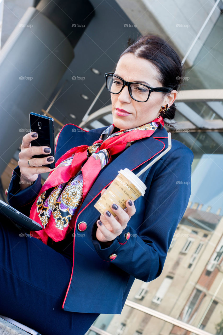 business woman multitasking. Business woman typing on phone with laptop on her lap and drinking coffee