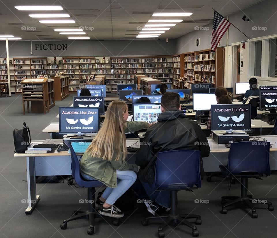 Teenage students working collaboratively on a project inside the computer lab section of the library 