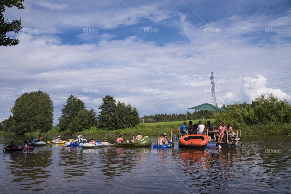 Helsinki, Finland – July 30, 2016: Unidentified people drafting down Vantaanjoki river on rubber dinghies, rafts and other inflatables at the annual Kaljakellunta (Beer Floating) festival taking place at the end of the July or beginning of the August. Festival which attracts hundreds of participants every year is a spontaneous gathering of people and there is no official organizer for the event.