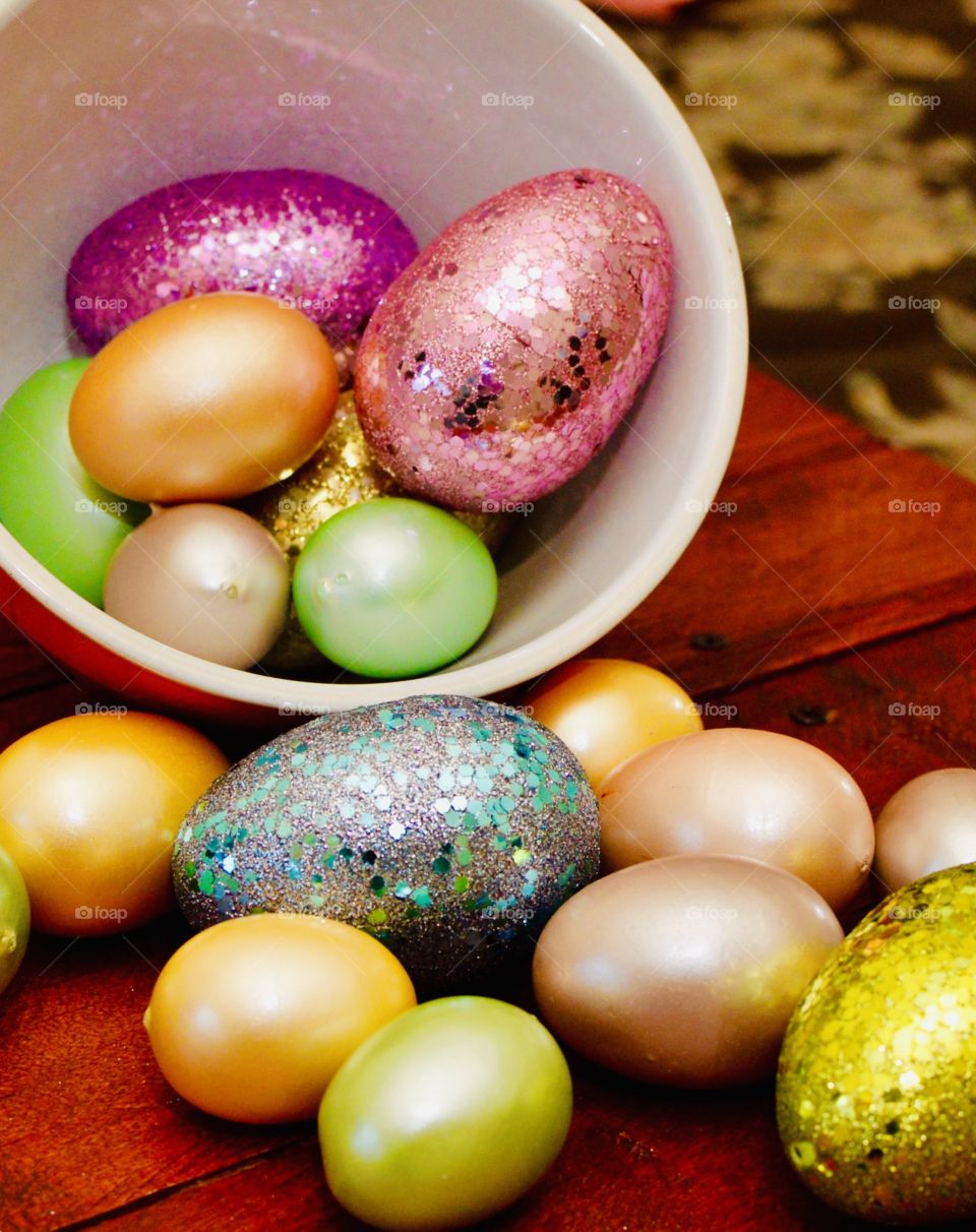 Bowl of colorful plastic eggs on a wooden backdrop 